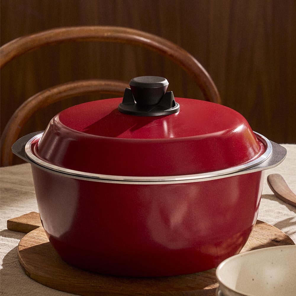Red enameled cast iron Dutch oven on a wooden surface with a blurred background