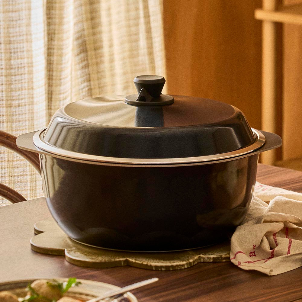 Black enameled cast iron Dutch oven on a wooden table with a blurred background