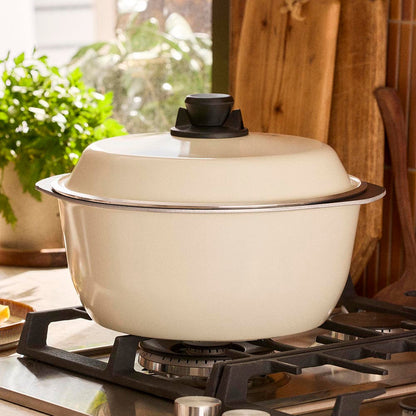 Beige enameled cast iron cookware on a stove with a wooden background
