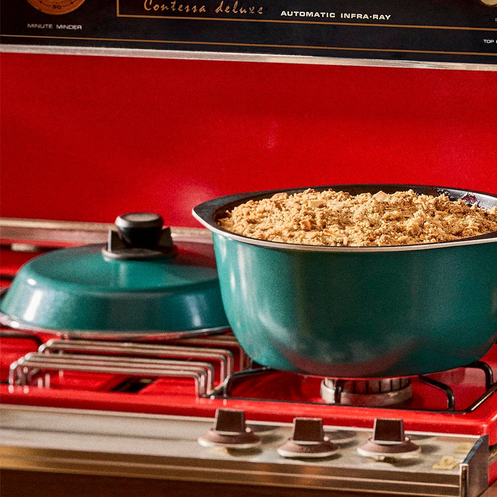 Teal pot on a red stove with food inside