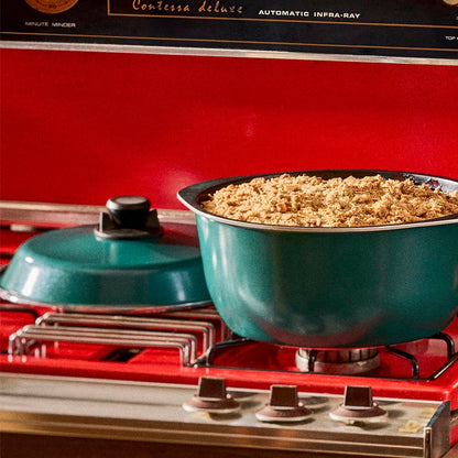 Teal pot on a red stove with food inside