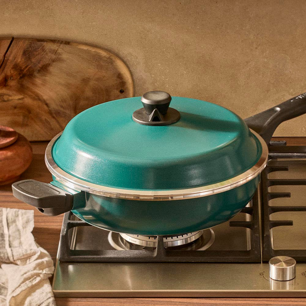 Teal frying pan with lid on a stove